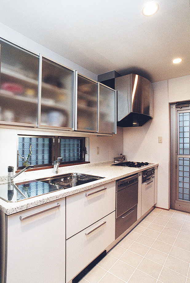 吊り戸収納扉にフロストガラスを使用した、大きめのシンクが料理をしやすいキッチン