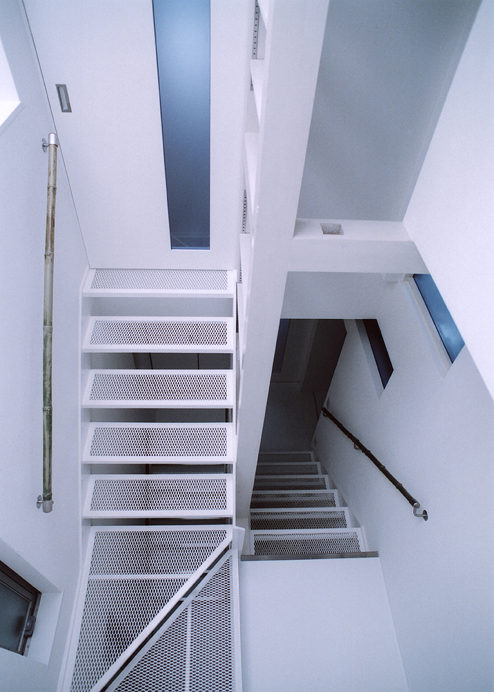 細長い敷地をデザインとして利用した、グレーチングメタルを通して明るい光が溢れる階段周り