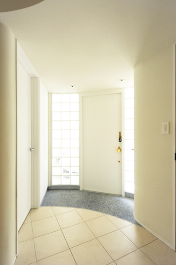 ガラスブロックに包まれた玄関ホールとシンプルモダンなデザインの玄関ドア