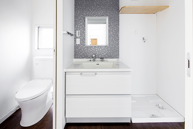 白い空間にグレーのタイルがモダンな雰囲気を醸し出す洗面・トイレ