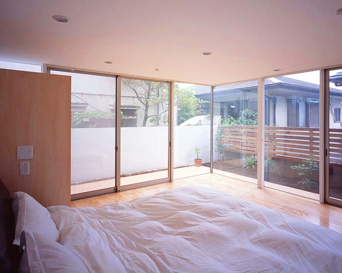 全面窓で柔らかな朝日が注ぐ寝室